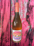 Bottle of wine with a colorful label against a pink and black textured background